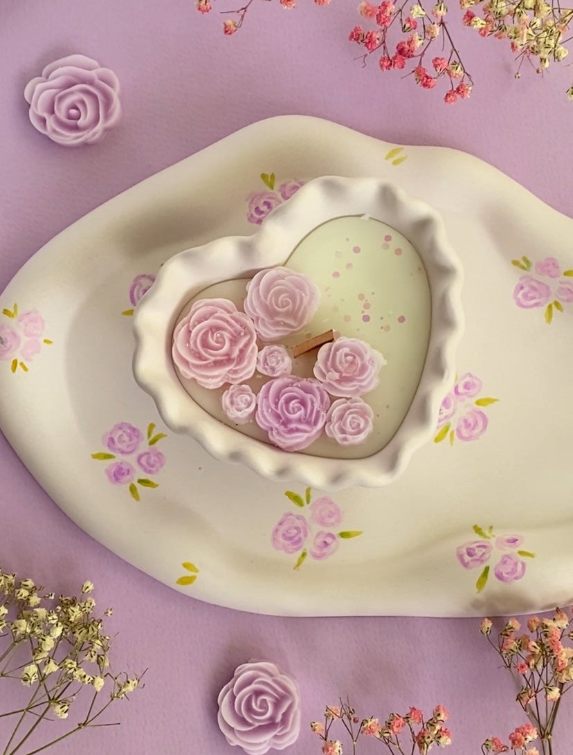 A wavy heart candle in white colour with lavender coloured rose candles